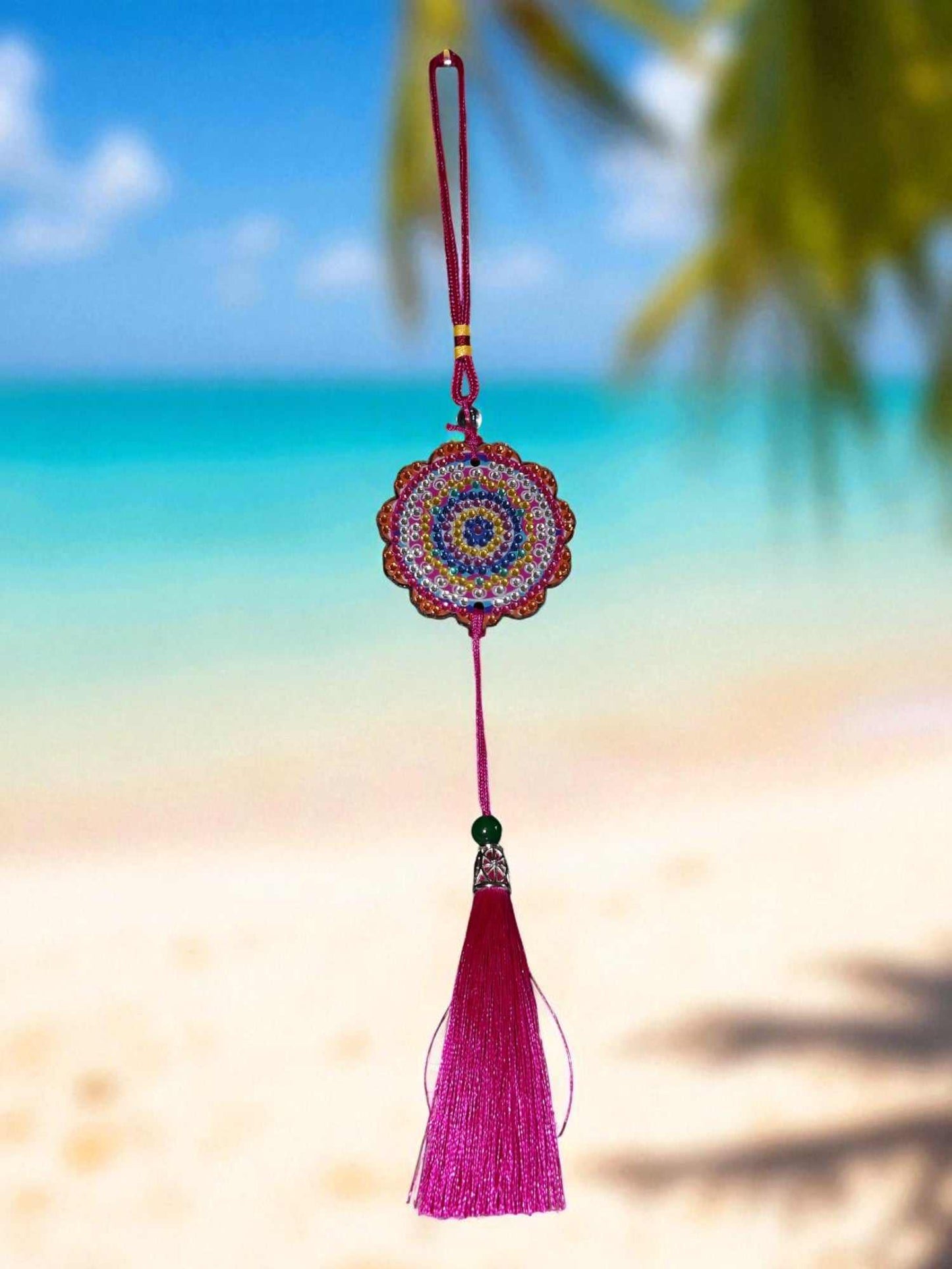Pink colorful design car ornament with tassel hanging against beach background