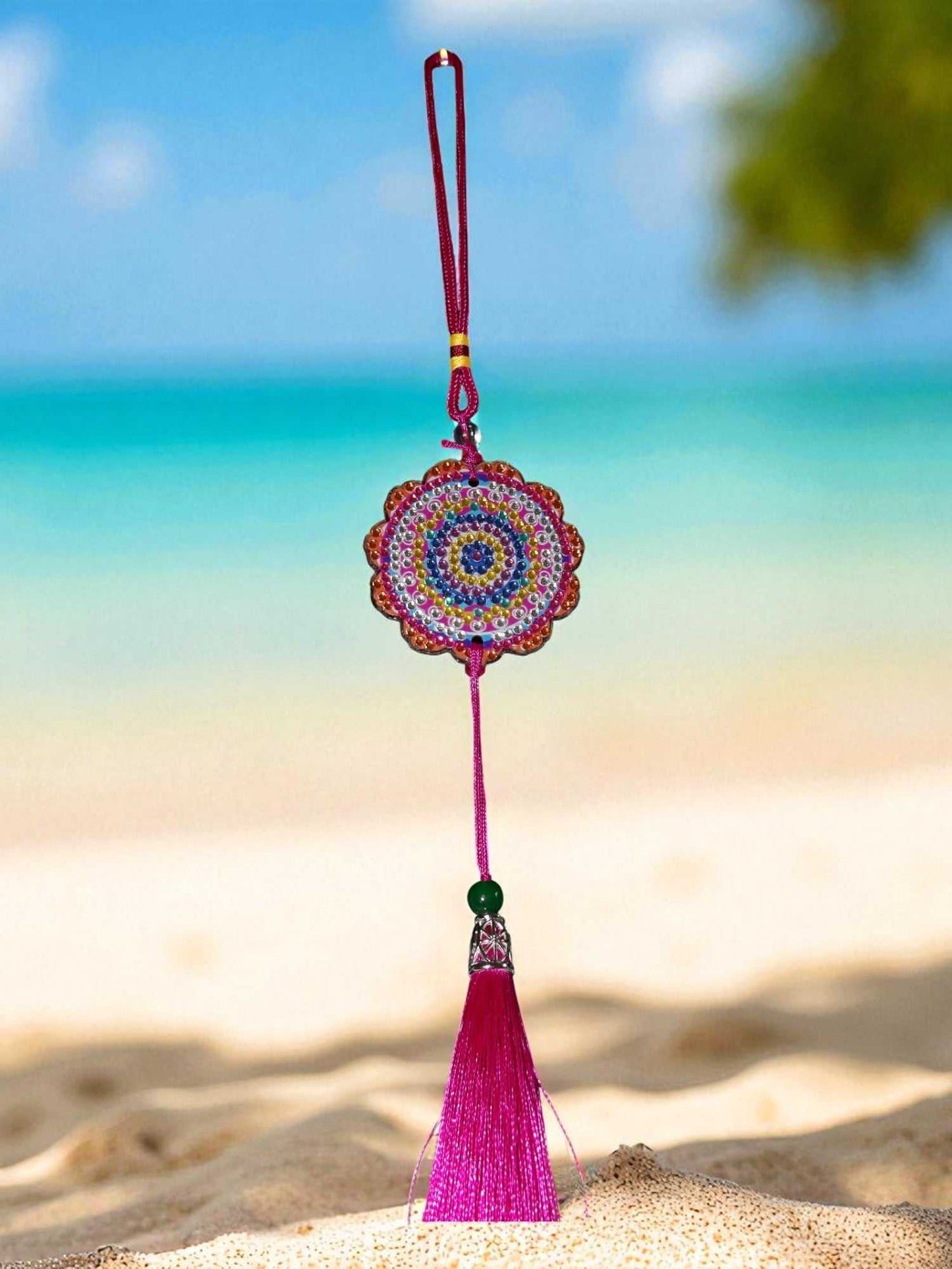 Pink colorful design car ornament with tassel hanging against beach background