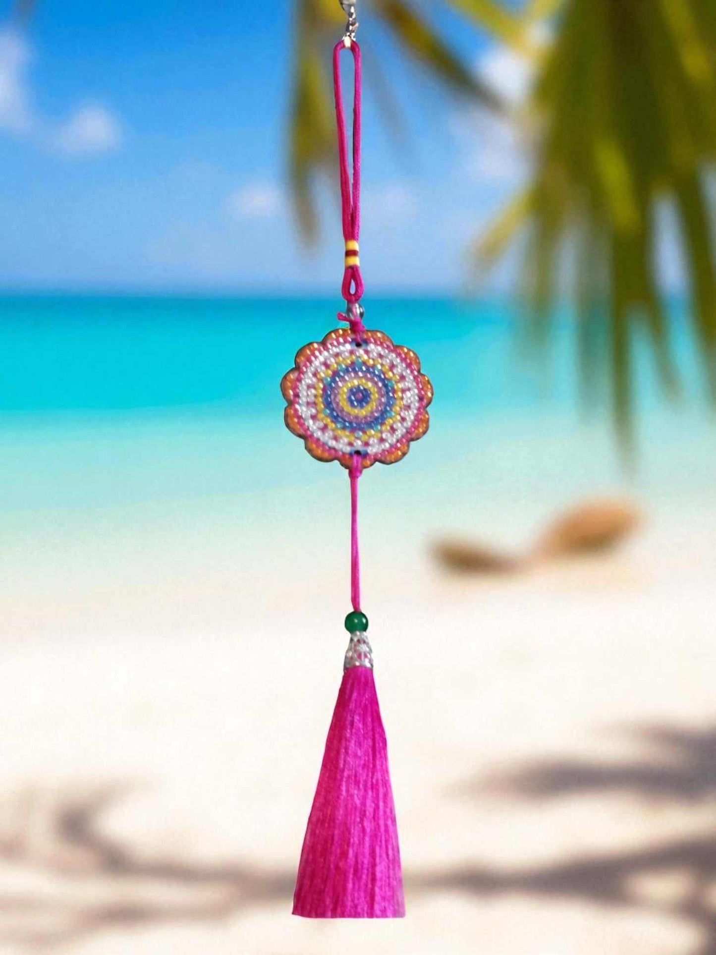 Pink colorful design car ornament with tassel hanging against beach background