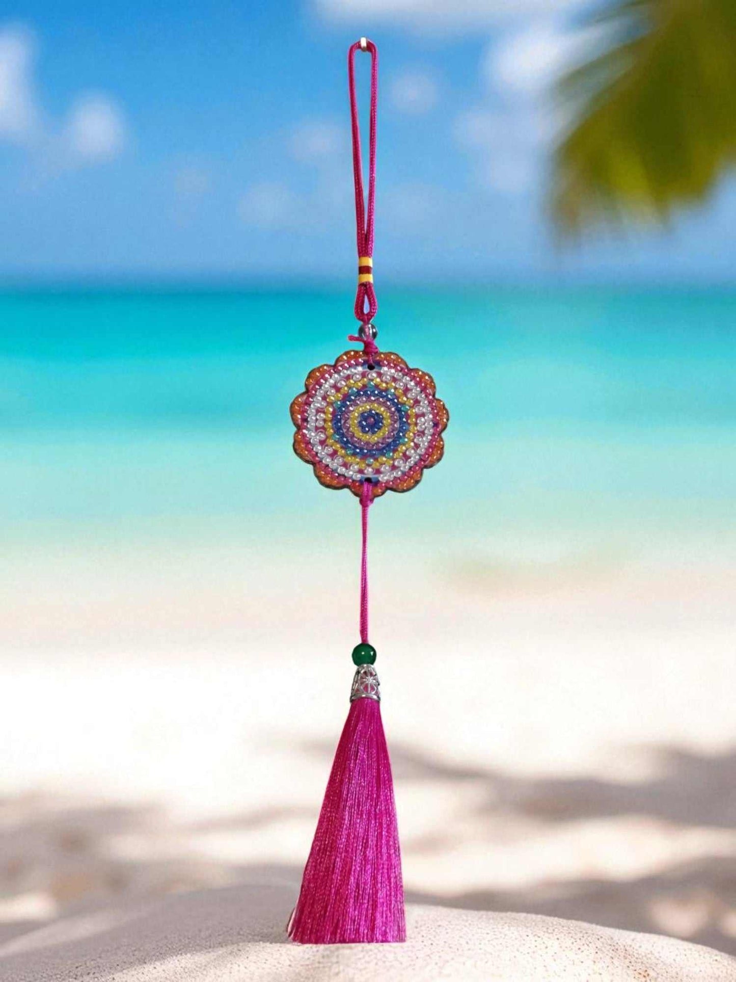 Pink colorful design car ornament with tassel hanging against beach background