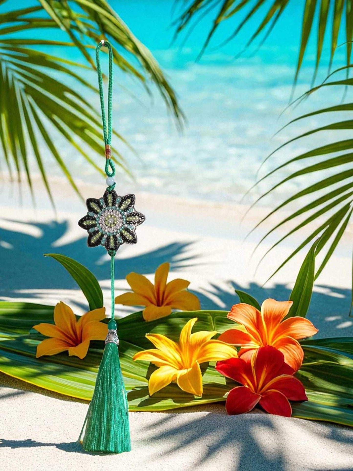 car ornament with beaded flower design and green tassel hanging against tropical beach background