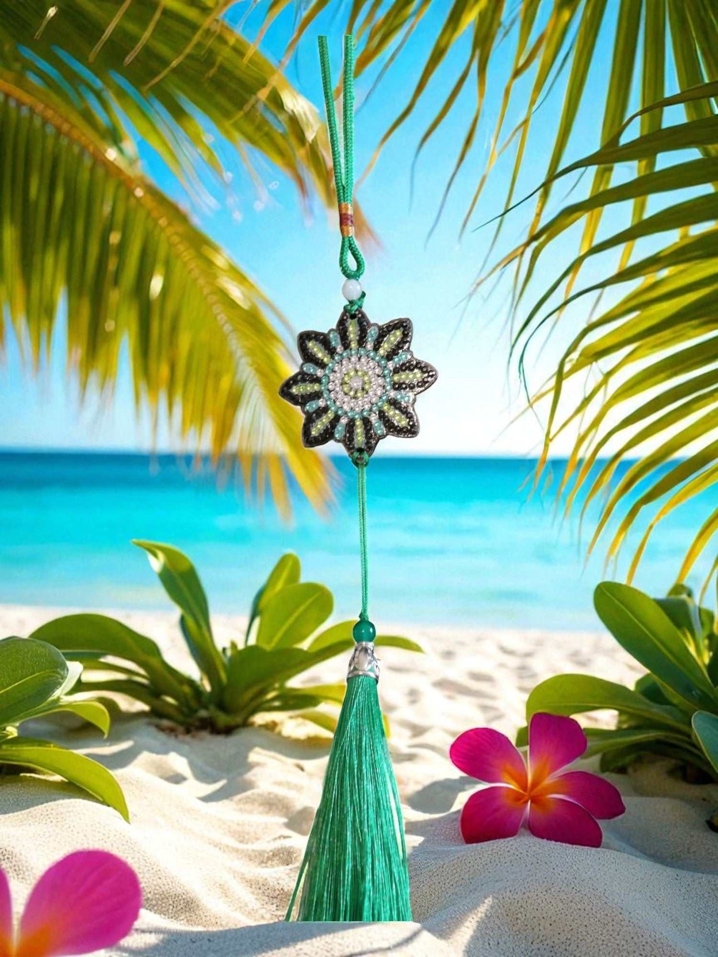 car ornament with beaded flower design and green tassel hanging against tropical beach background