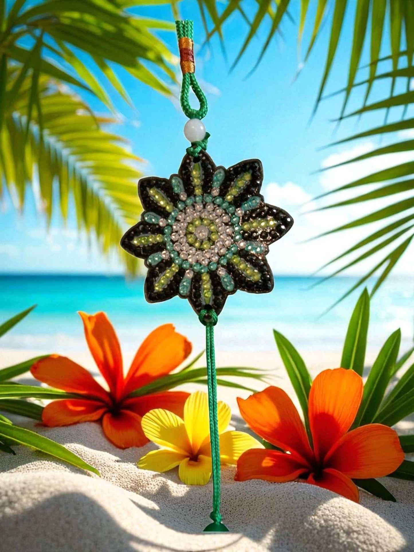 car ornament with beaded flower design and green tassel hanging against tropical beach background