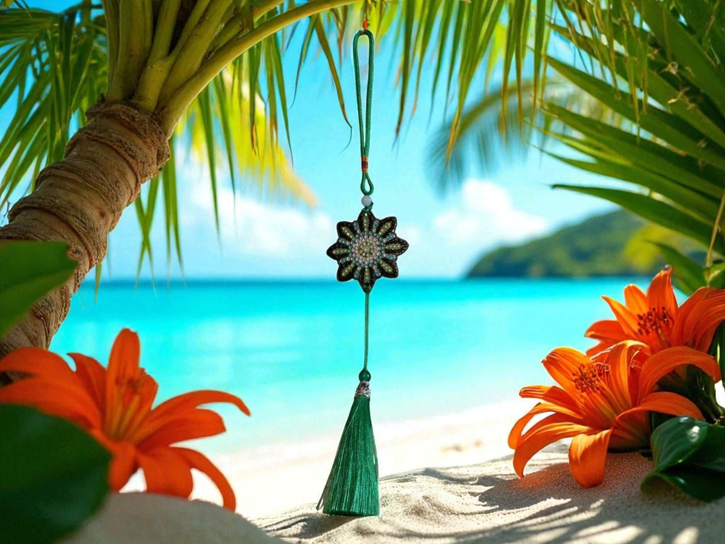 car ornament with beaded flower design and green tassel hanging against tropical beach background