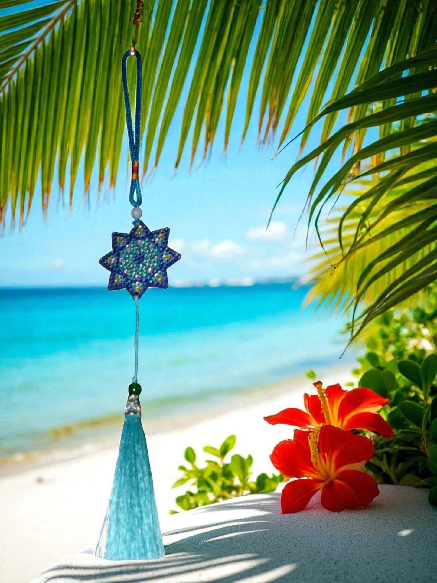 Light Blue Star colorful car ornaments hanging with beach background and red tropical flowers
