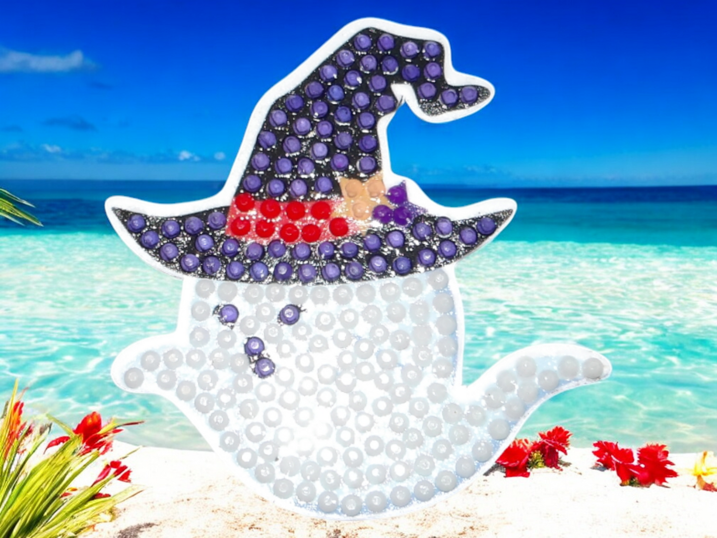Glow in the dark ghost magnet wearing a blue hat with red band on beach background