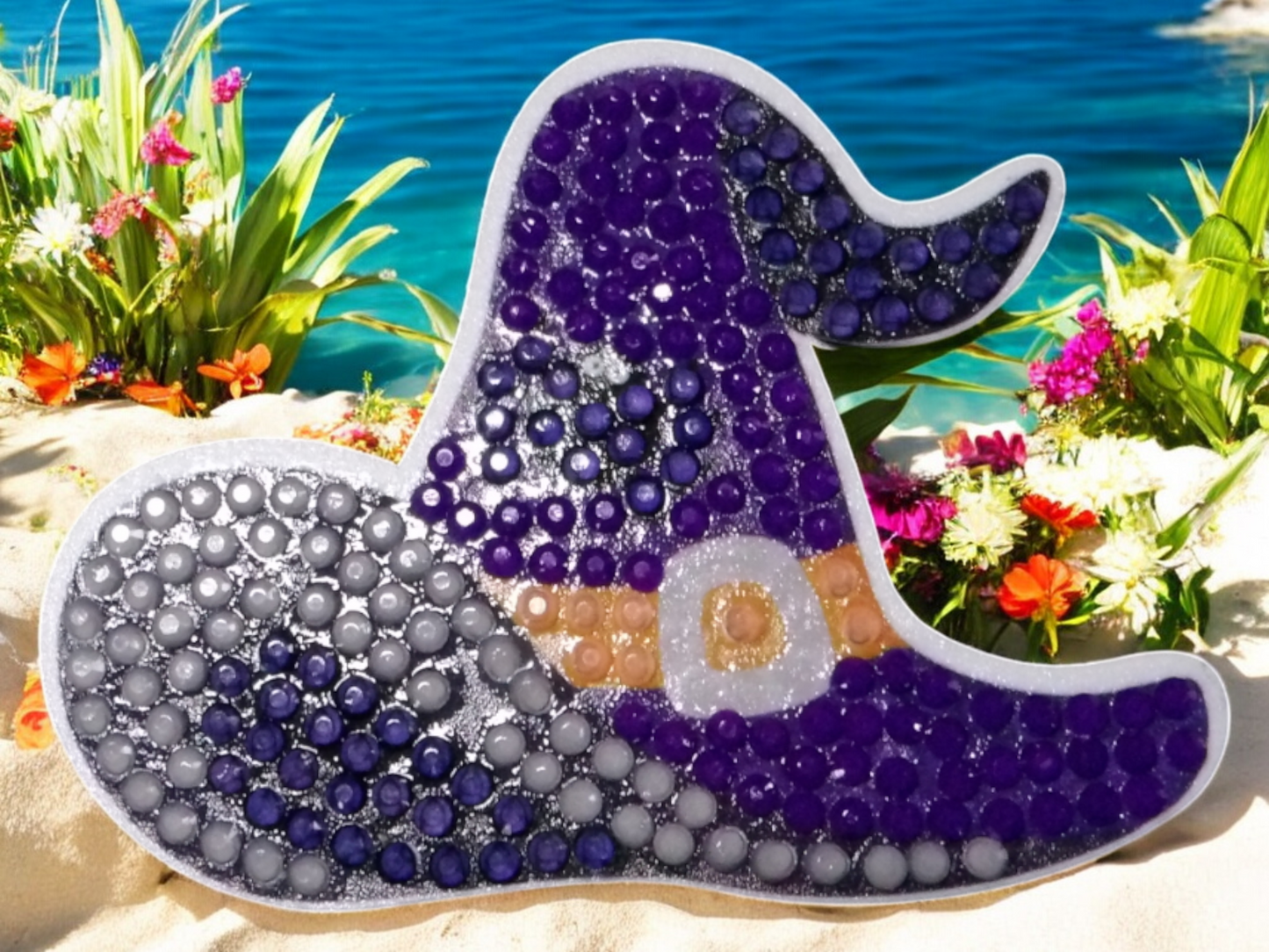 Glow in the dark purple-blue witches hat magnet with sparkling details on beach background