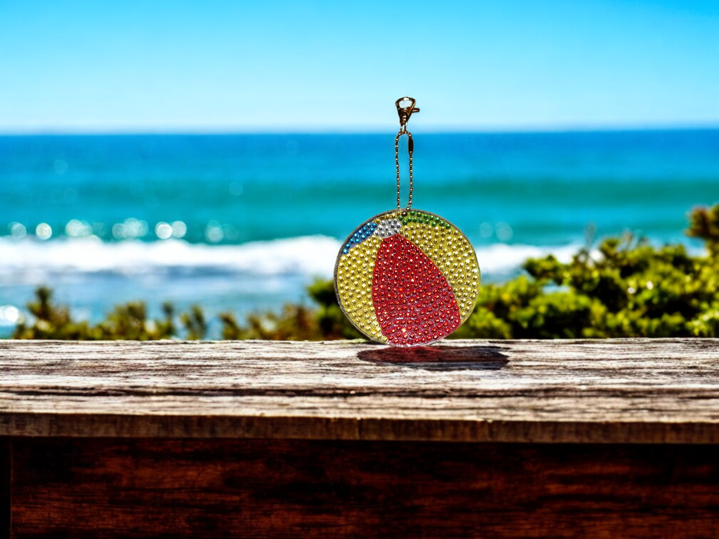 Colorful beach ball keychain with rhinestones hanging by the ocean background