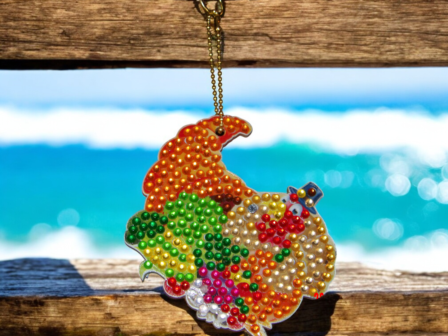 Colorful Gord Keychain decorated with vibrant beads hanging by a wooden beach background