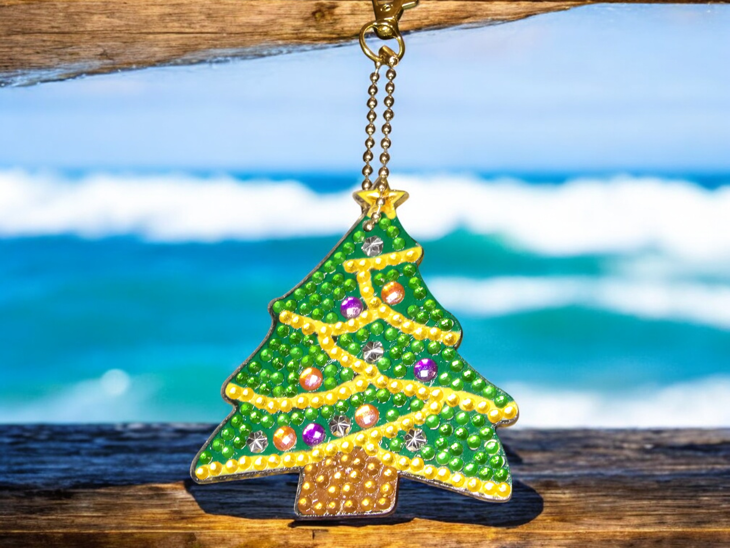 Decorated tree keychain with colorful beads hanging by the ocean on a wooden surface