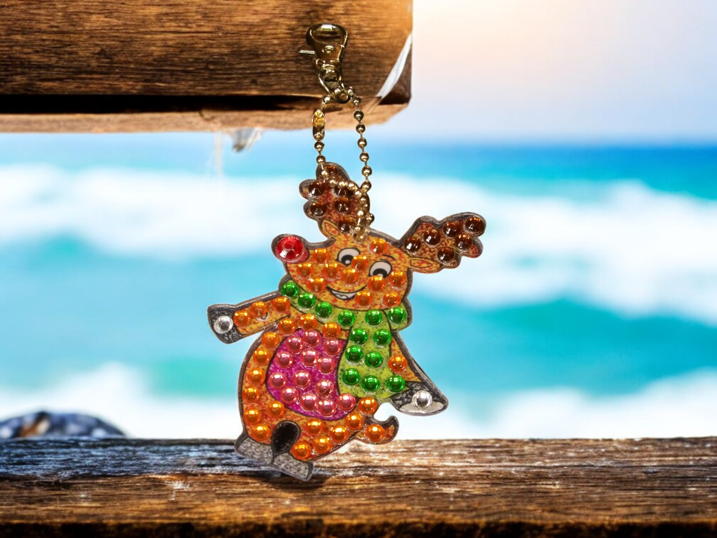 Colorful moose keychain with sparkling beads hanging by the beach background