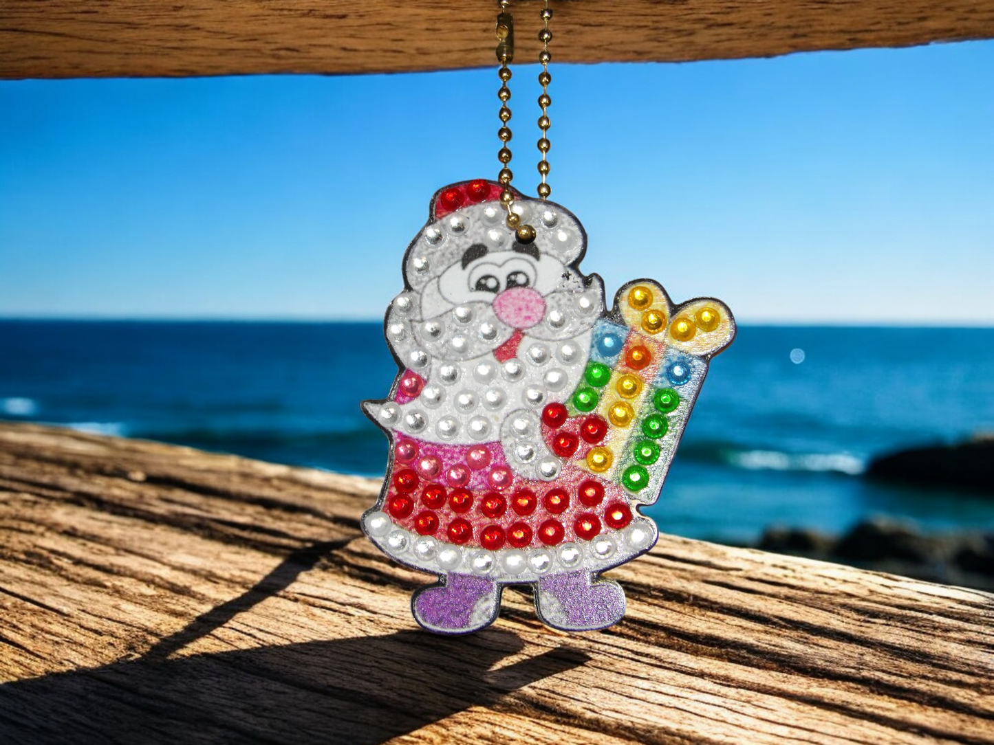 Santa w/Present keychain hanging with ocean background and wooden surface