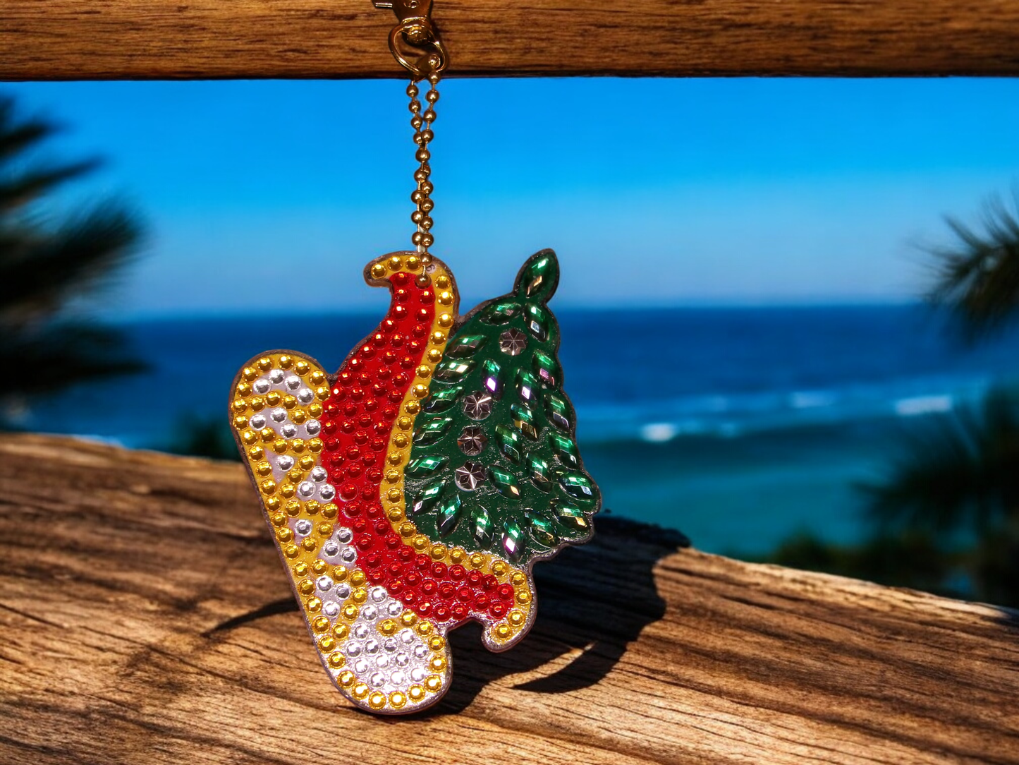 Colorful sleigh with Christmas tree keychain hanging on wooden surface with ocean background