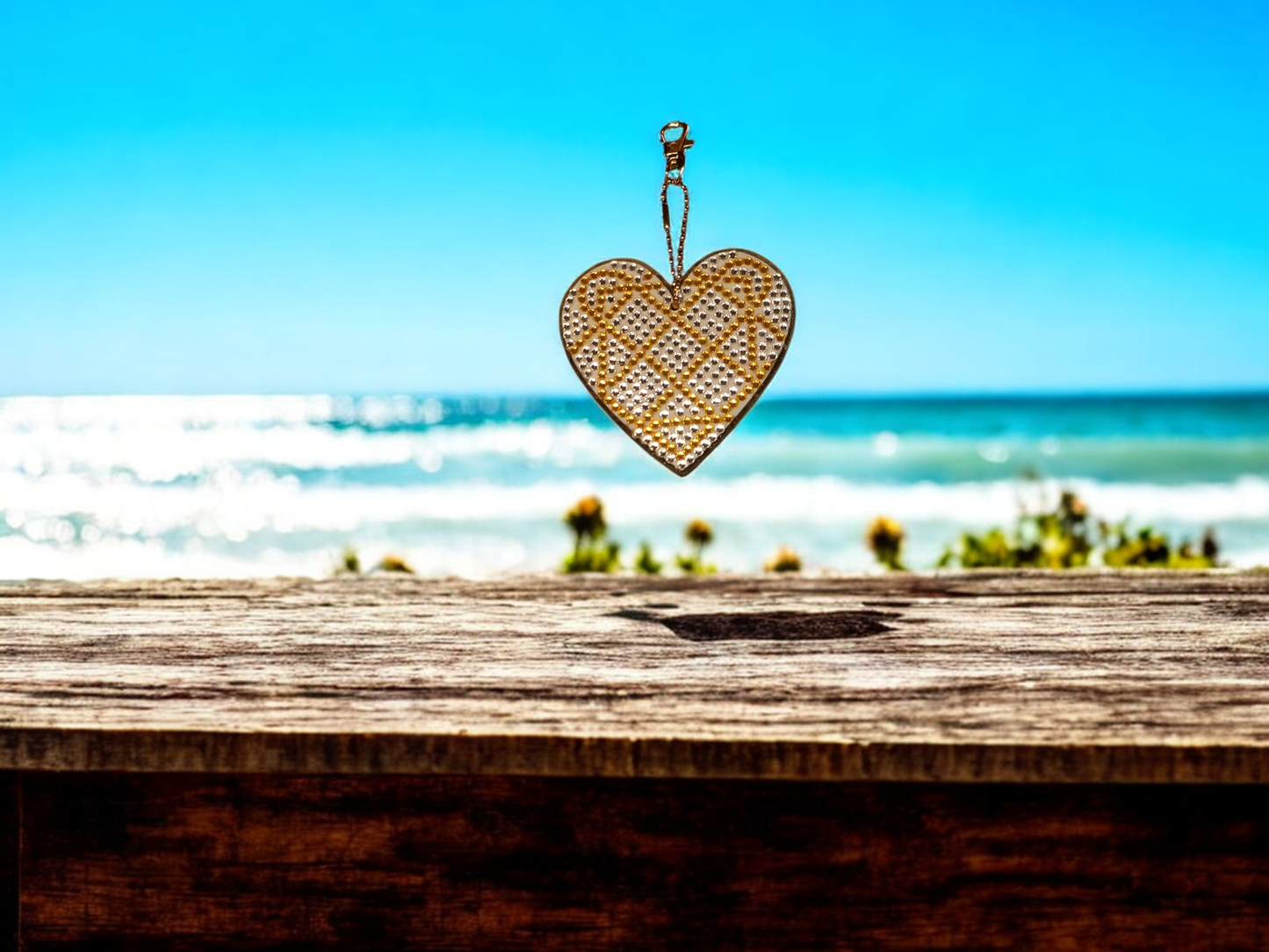 Yellow and crystal large heart-shaped keychain hanging against a beach background