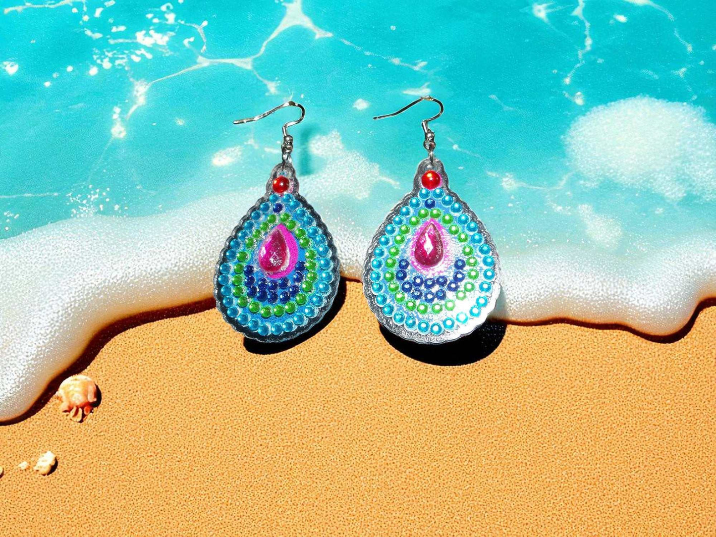 Blue green round handmade earrings with colorful bead pattern on beach background