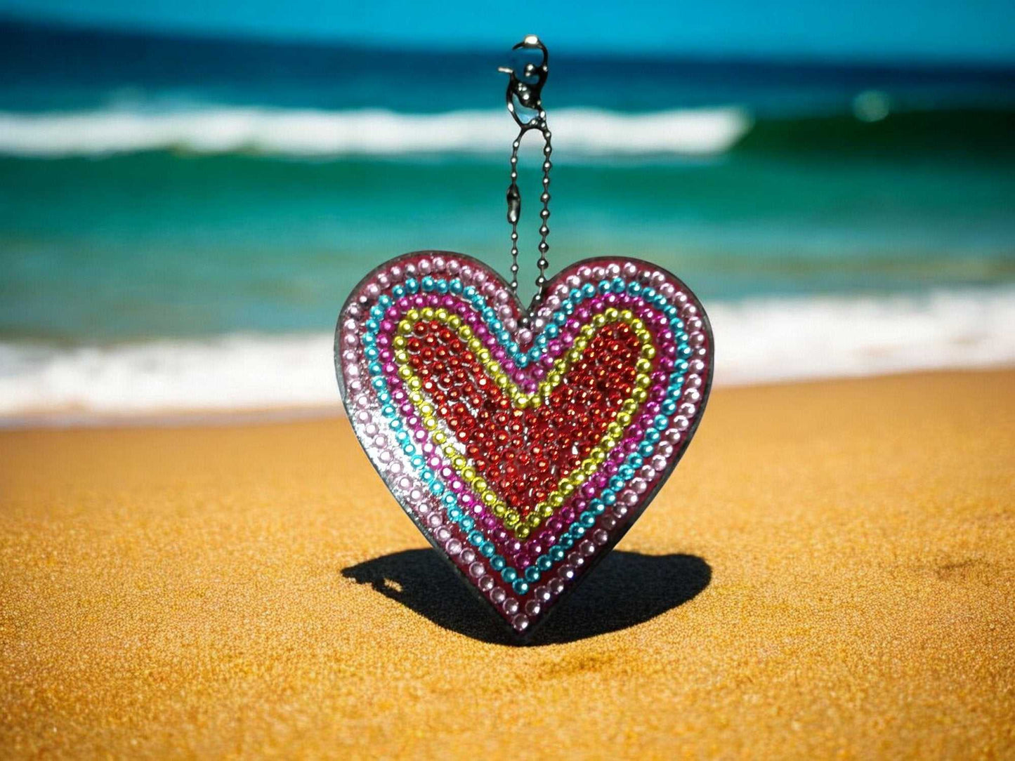 Red Center Heart Keychain with colorful beads hanging on a chain at the beach
