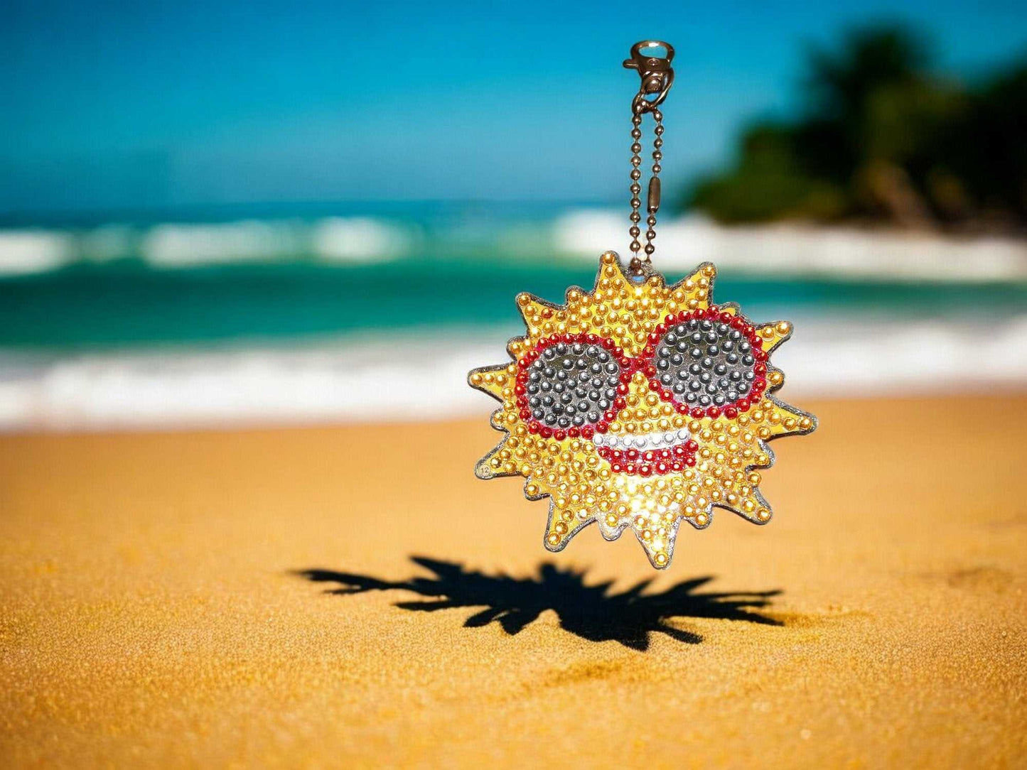 Golden Bright Sun Keychain with sunglasses hanging on beach background