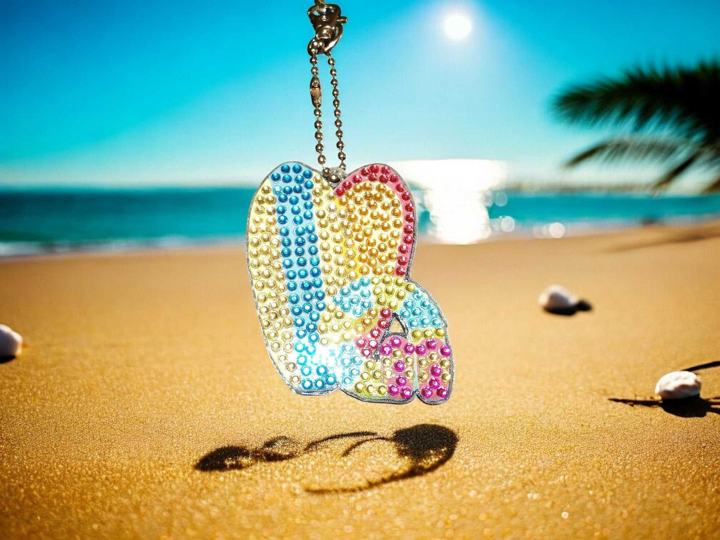 Colorful Surfs Up Surf Boards Keychain hanging on beach with ocean background