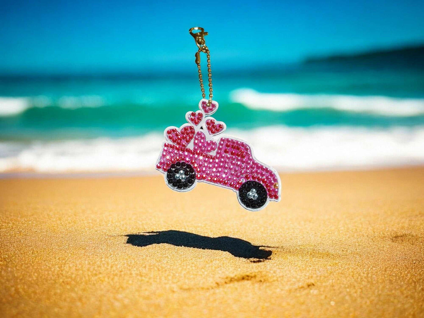 Pink Heart Pick Up Truck keychain with rhinestones on sandy beach background