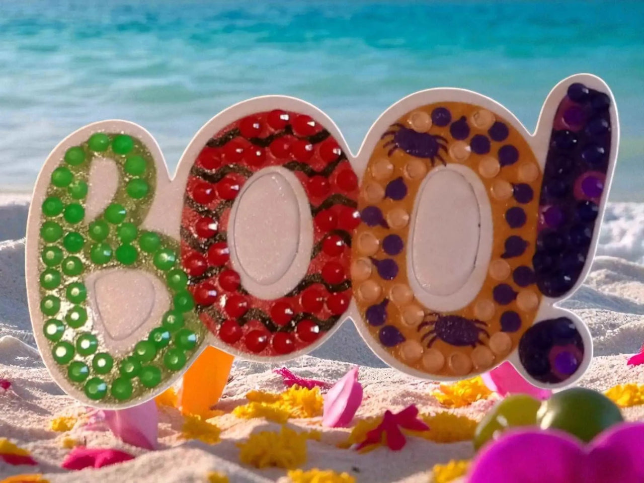 Glow in the dark BOO magnet with colorful beads and spider design on sandy beach background