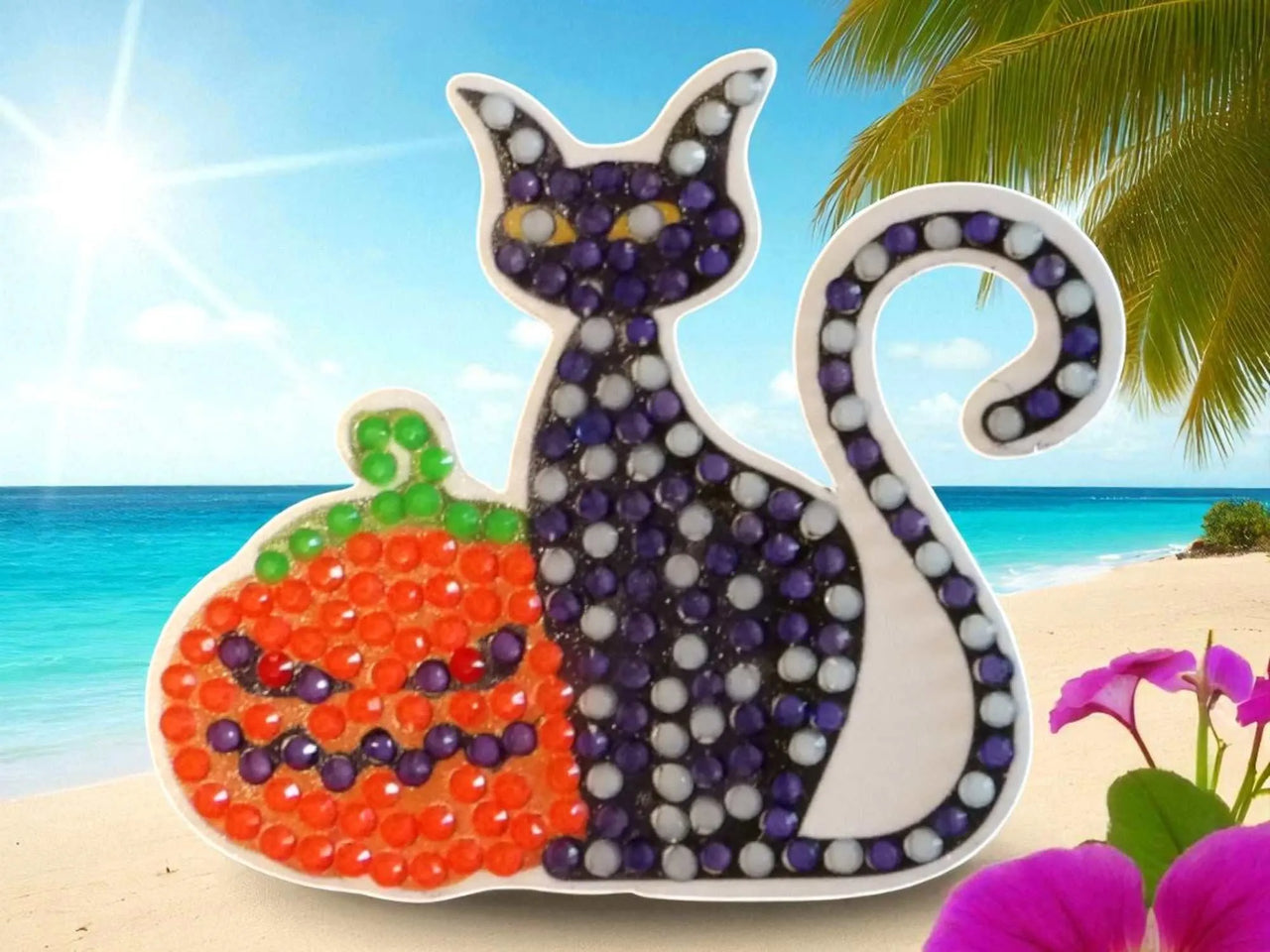 Glow in the dark black cat and pumpkin magnet with colorful beads on a beach background