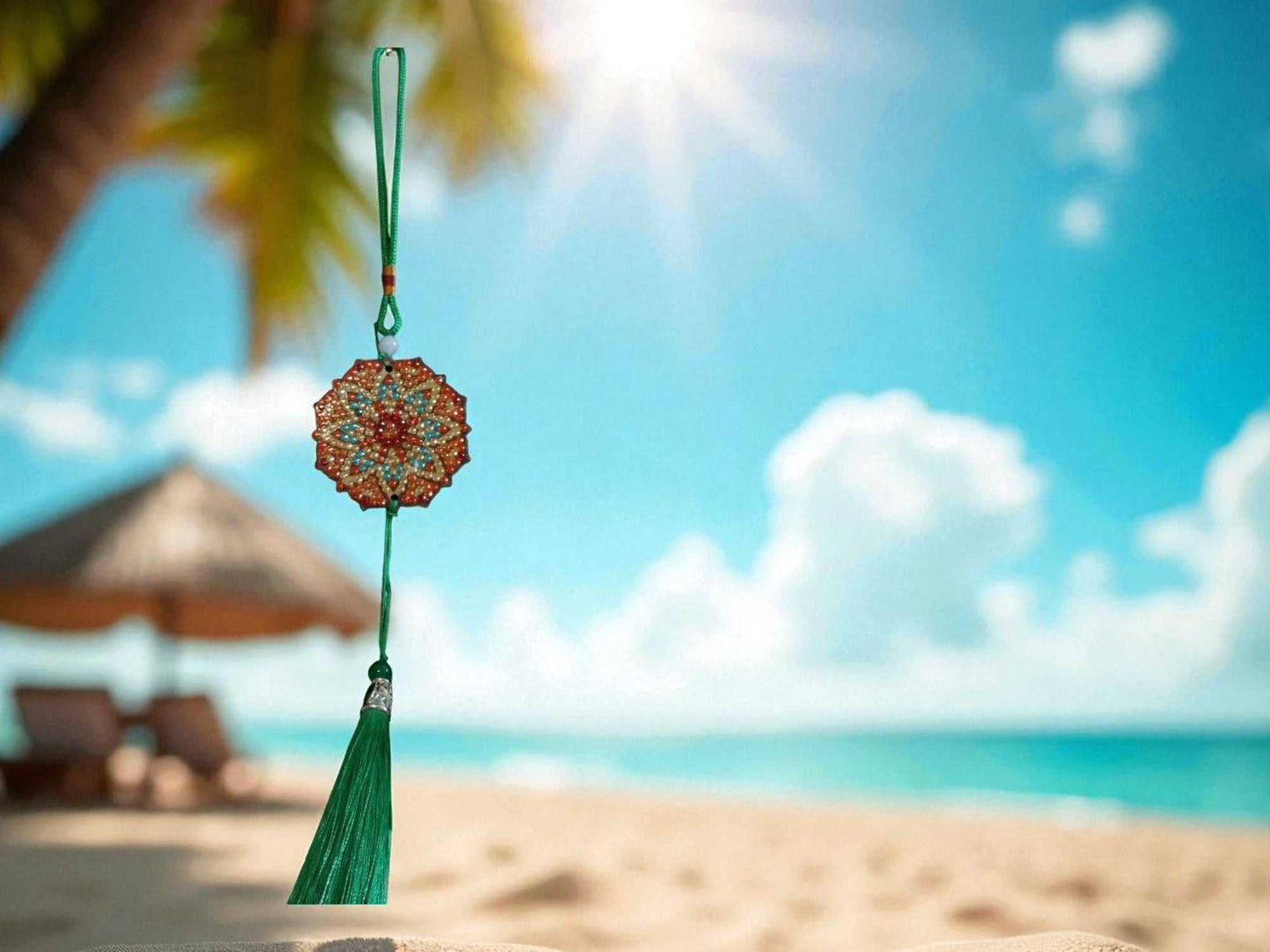 Green Red Design car ornament with tassel hanging against beach background