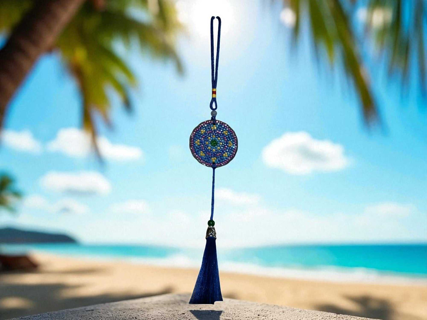 Blue and yellow colorful car ornament hanging with tassel against beach background