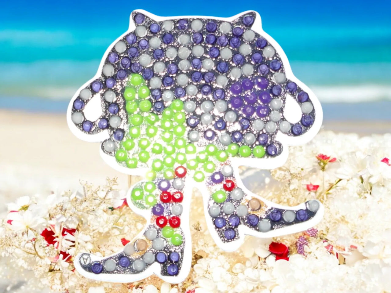 Glow in the dark dancing upside down pot magnet with colorful beads against beach background