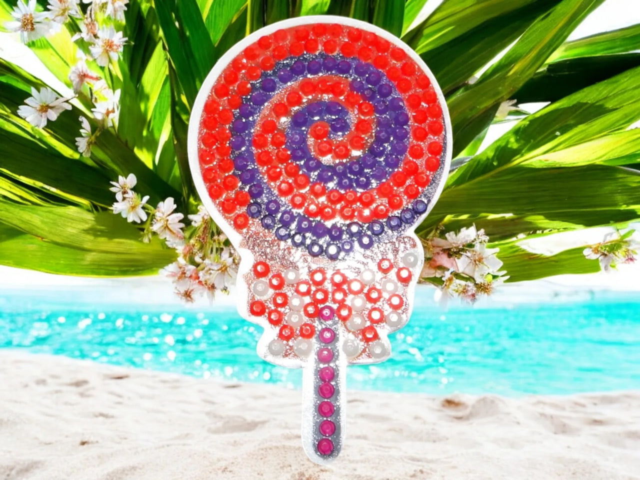 Glow in the dark colorful swirly lollipop magnet on blue surface with greenery accents