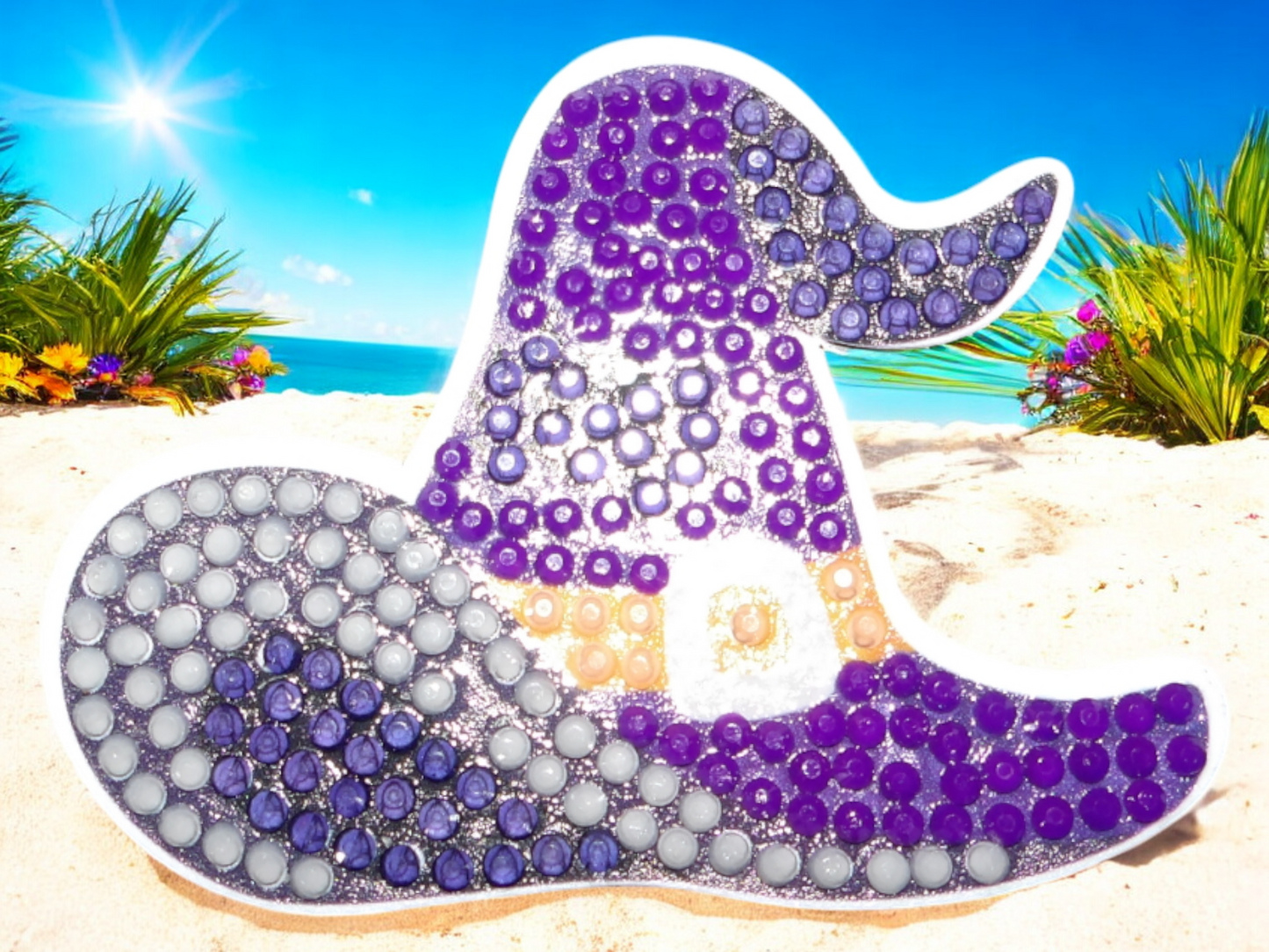 Glow in the dark purple-blue witches hat magnet with sparkling details on beach background