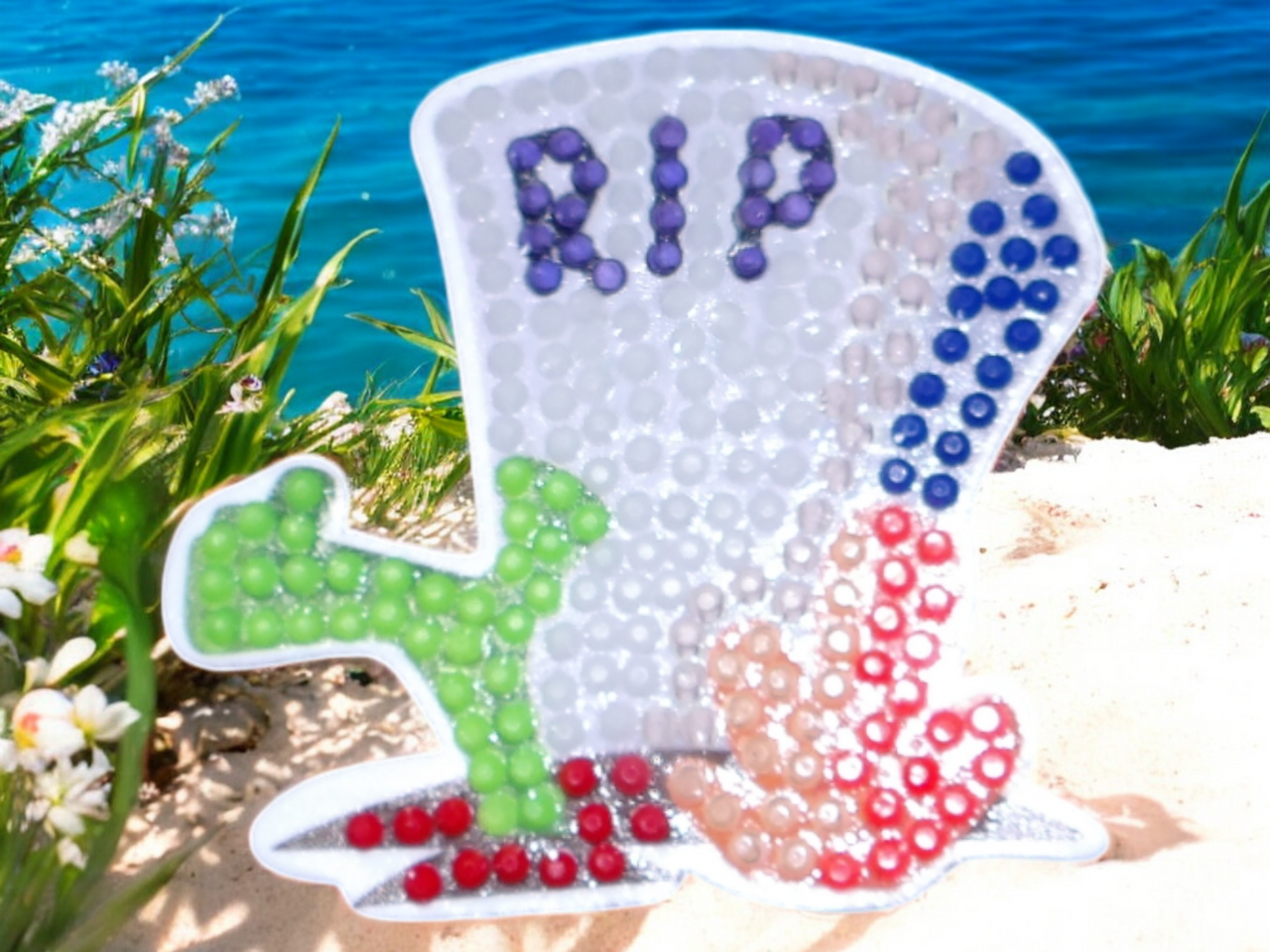 Colorful glow in the dark RIP headstone magnet with vibrant bead design outdoors