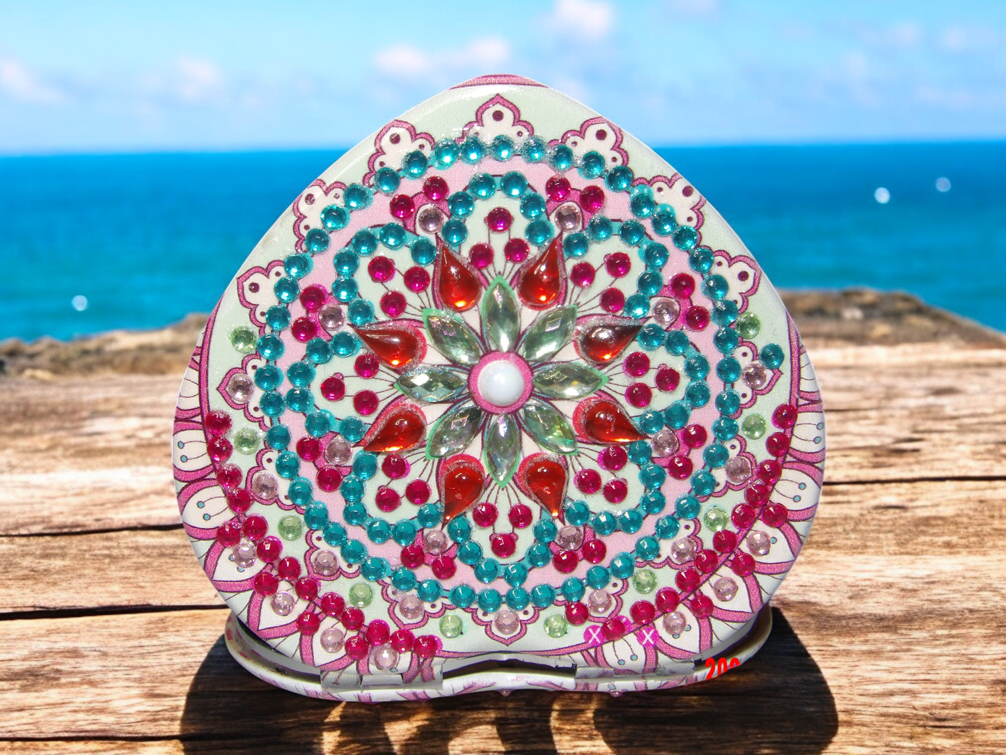 Red colorful heart mandala design pocket mirror with magnification by the sea