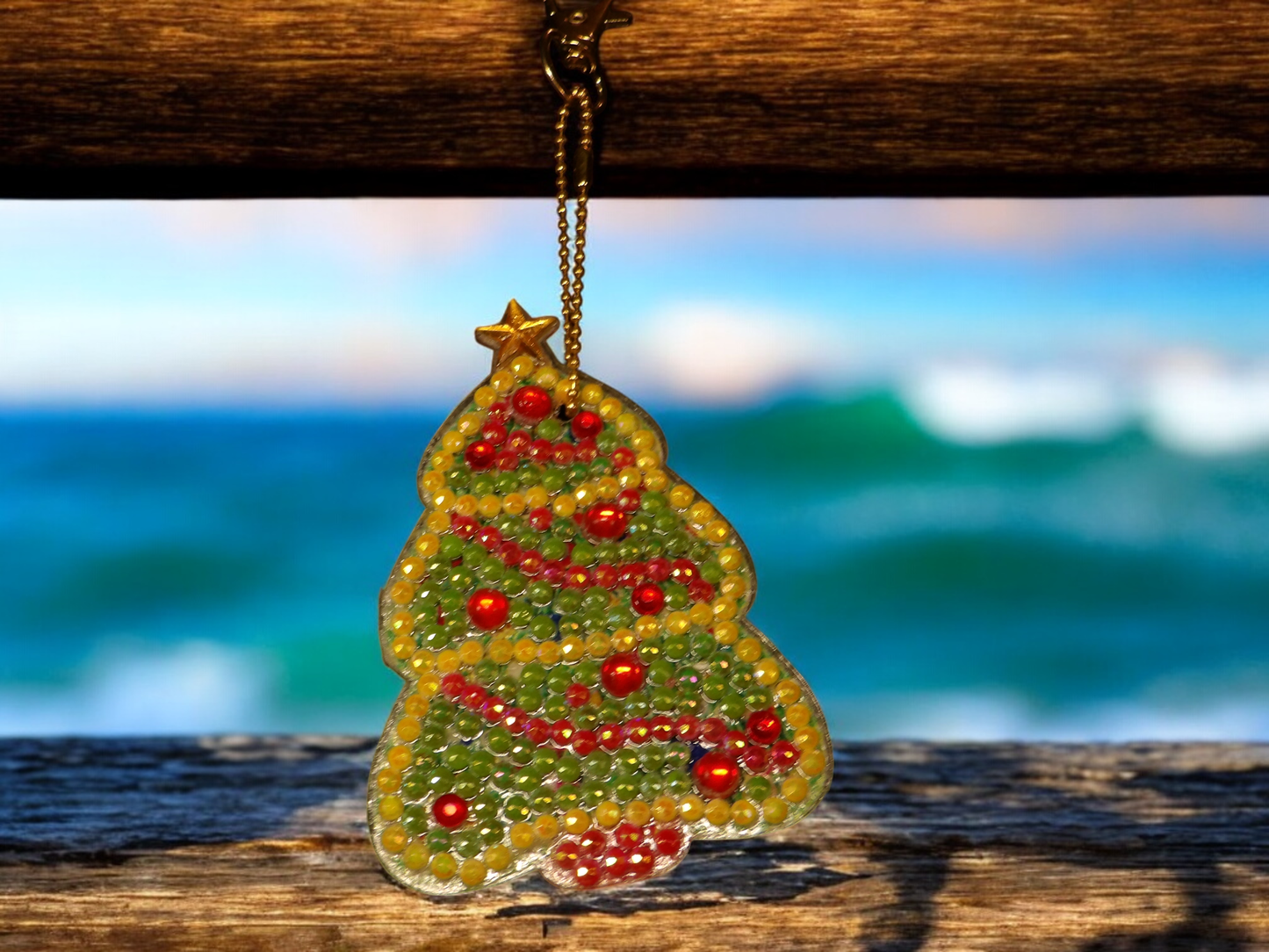 Colorful tree keychain with beads hanging on wooden surface with ocean background