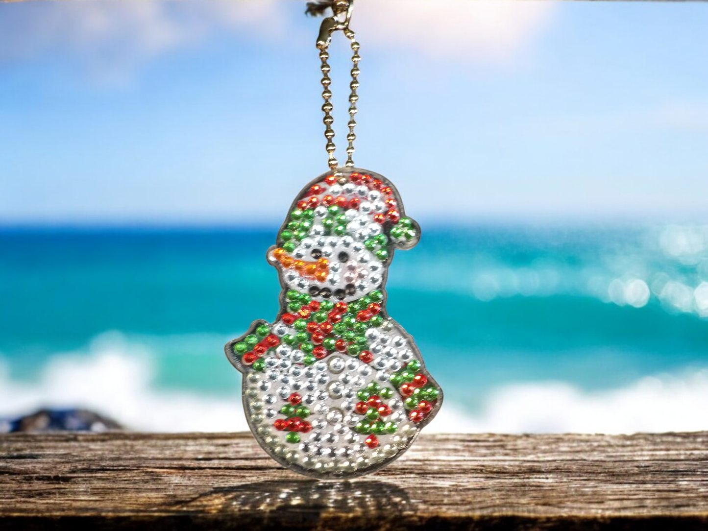 Green tip hat snowman keychain hanging with ocean background