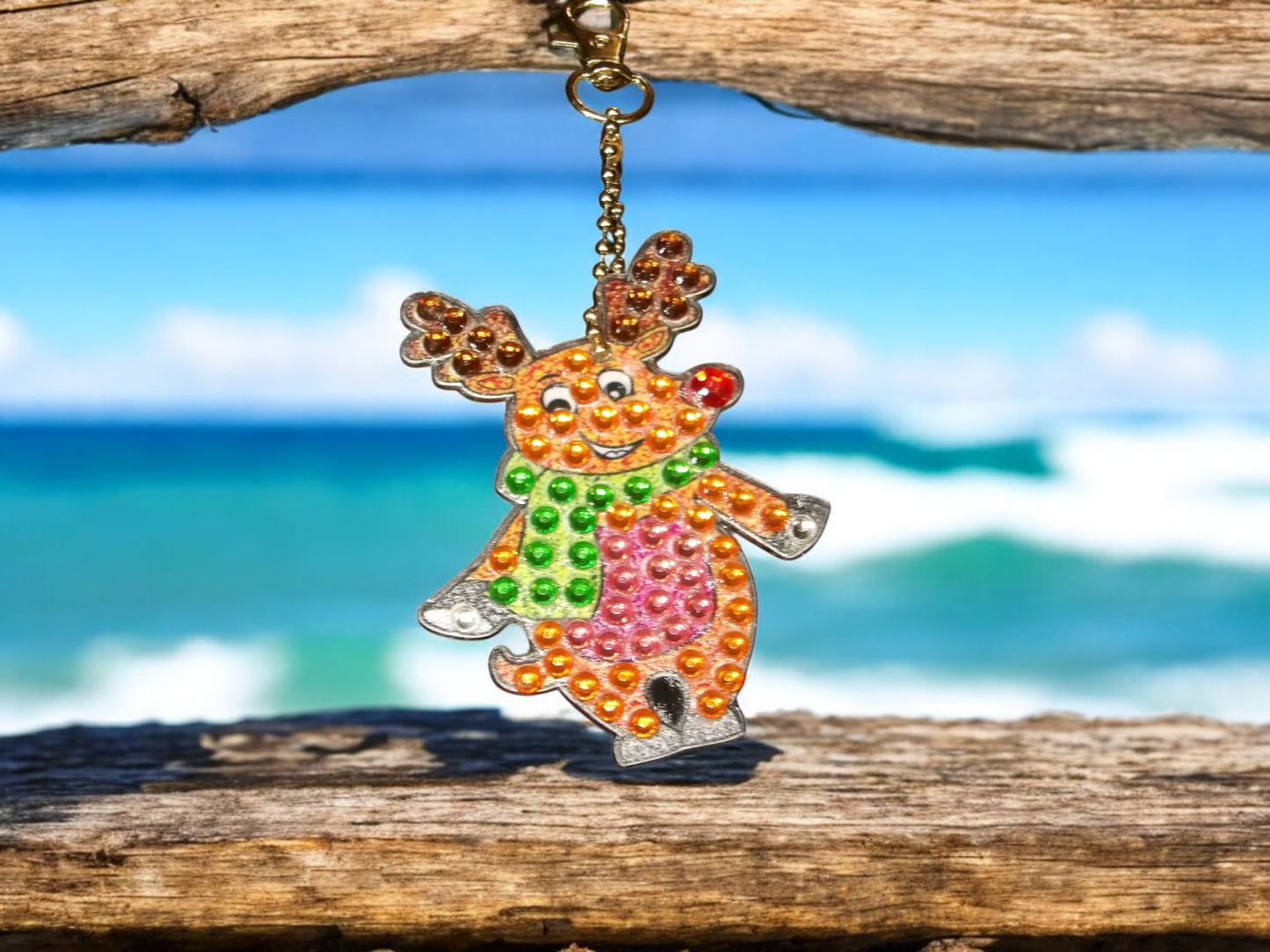 Colorful moose keychain with beads hanging on wooden surface by the beach