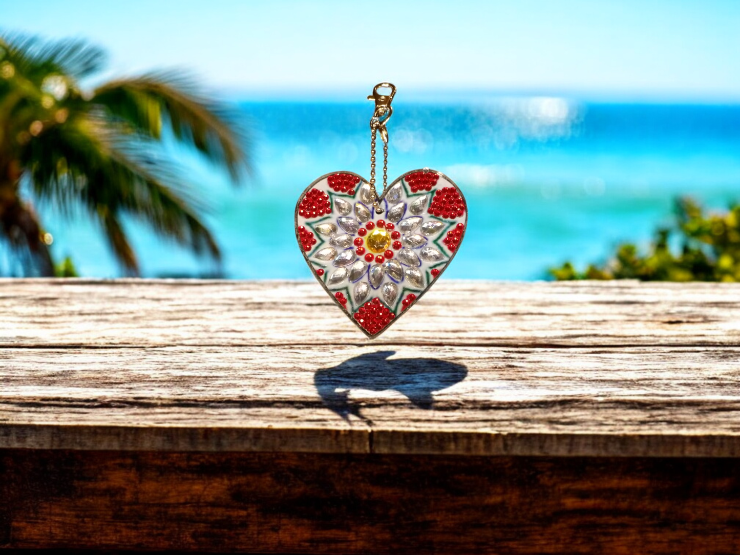 Large unique red and white heart keychain hanging outdoors with ocean background