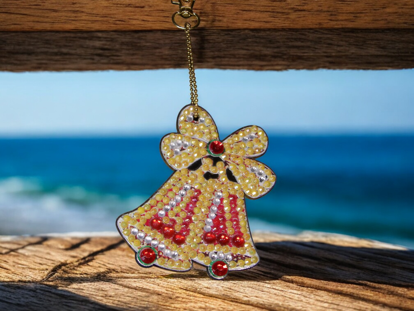 Yellow and red bells keychain with decorative beads hanging outdoors by the sea